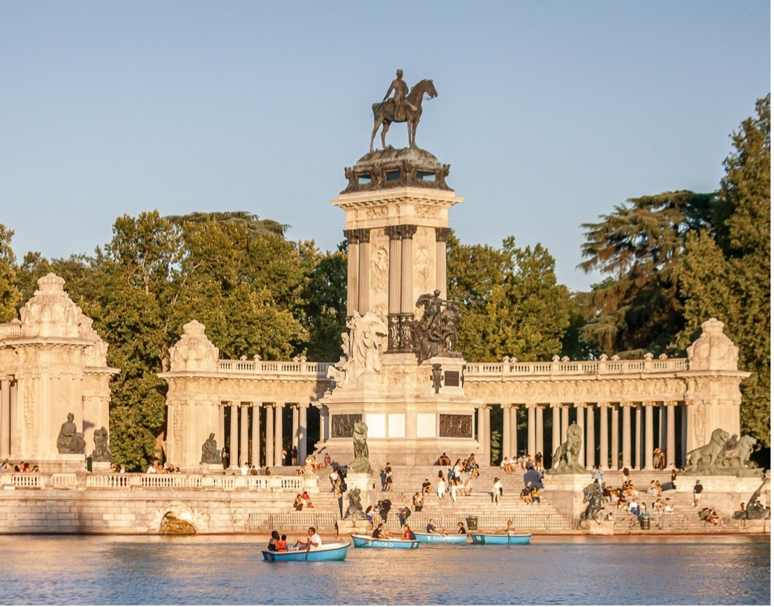 boats rowing on a river in front of a statue with a man on a horse