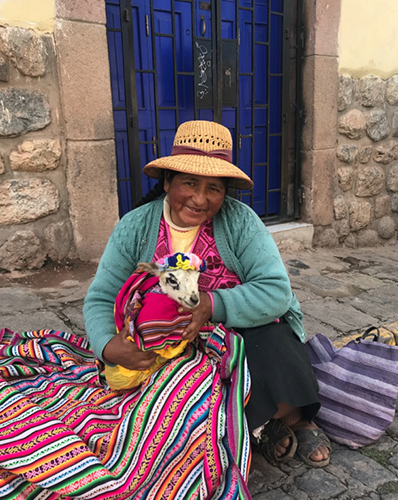 Peruvian Woman with young goat wrapped in a colorful blanket